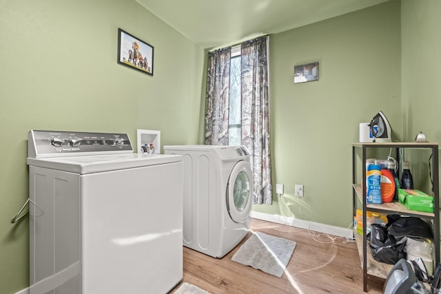 washroom featuring washer and dryer, laundry area, baseboards, and wood finished floors