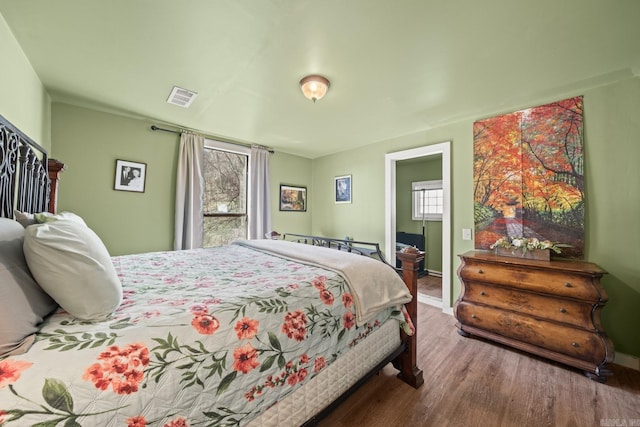 bedroom featuring visible vents, baseboards, and wood finished floors