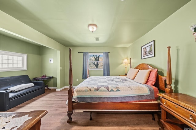 bedroom with baseboards, visible vents, and wood finished floors