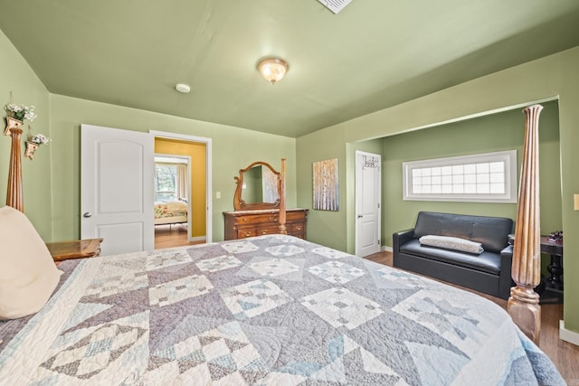 bedroom with multiple windows, baseboards, and wood finished floors