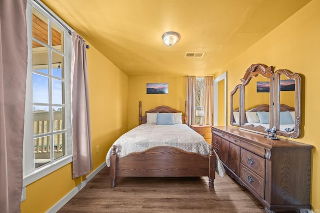 bedroom with visible vents, baseboards, and wood finished floors