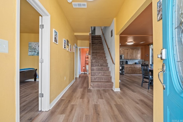 entryway featuring wood finished floors, visible vents, baseboards, and stairs