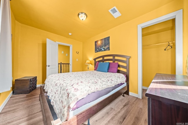 bedroom featuring baseboards, visible vents, and wood finished floors