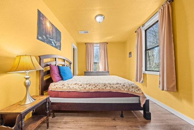 bedroom featuring baseboards, visible vents, and wood finished floors