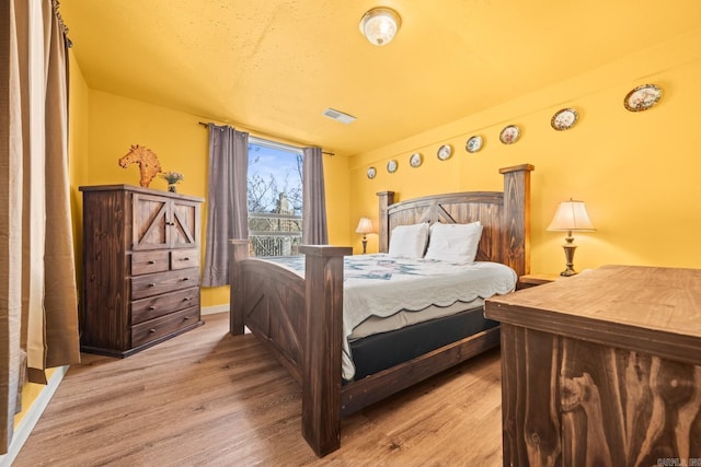 bedroom featuring access to outside, visible vents, and wood finished floors