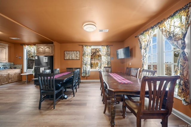 dining room featuring light wood-type flooring, visible vents, and baseboards