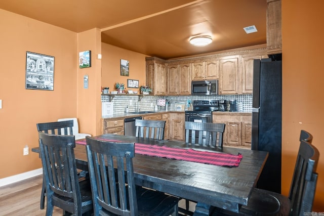 kitchen featuring stainless steel appliances, a sink, visible vents, light wood-type flooring, and tasteful backsplash