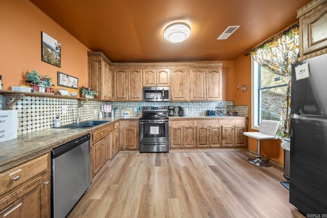 kitchen featuring tasteful backsplash, visible vents, brown cabinetry, appliances with stainless steel finishes, and a sink