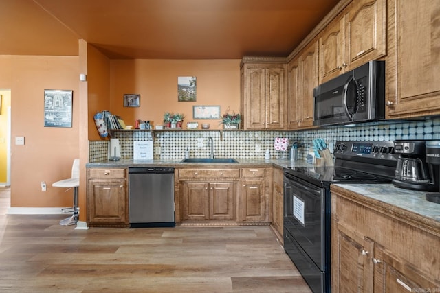 kitchen featuring black range with electric stovetop, a sink, light wood-style floors, stainless steel dishwasher, and tasteful backsplash