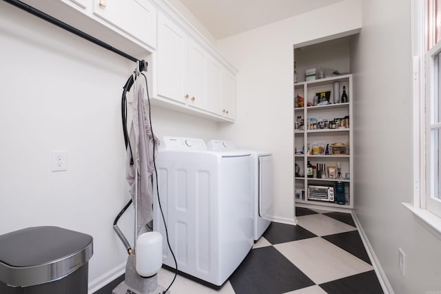 washroom with light floors, baseboards, washer and dryer, and cabinet space