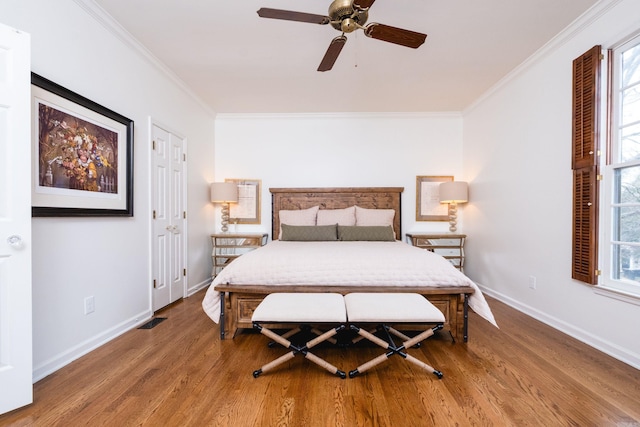 bedroom featuring baseboards, wood finished floors, a ceiling fan, and crown molding