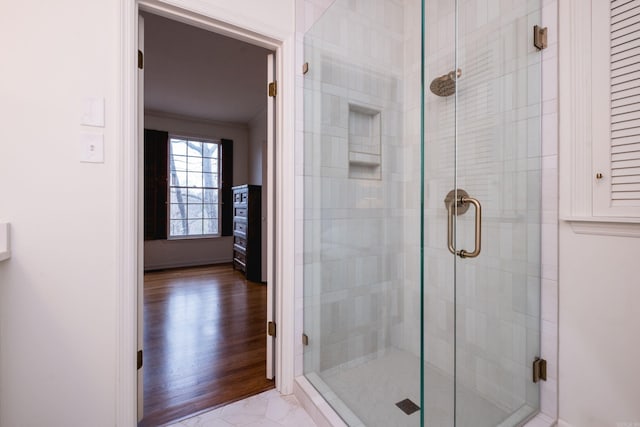 bathroom with marble finish floor, crown molding, and a shower stall