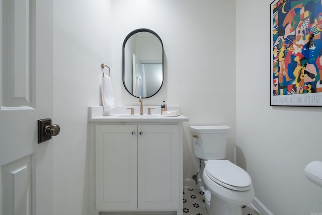 bathroom with baseboards, vanity, and toilet