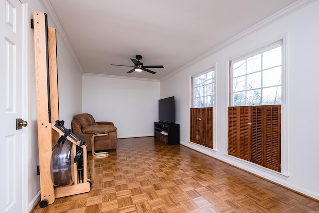 living area with ceiling fan, baseboards, and crown molding