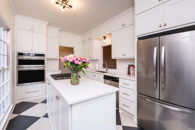 kitchen with dark floors, a center island, stainless steel appliances, light countertops, and white cabinets