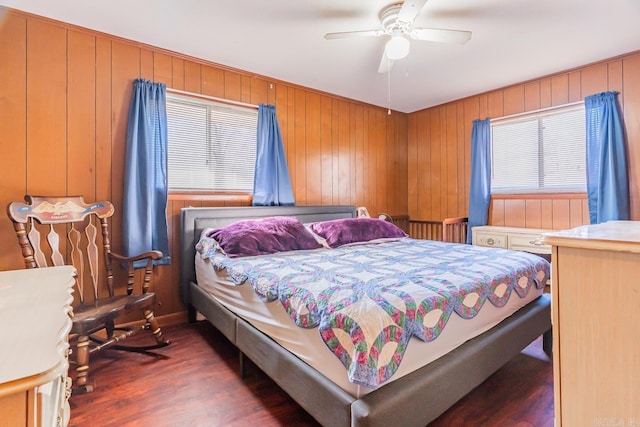 bedroom with ceiling fan, wooden walls, and wood finished floors