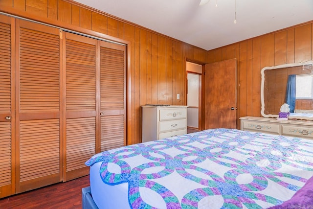 bedroom featuring wood walls, dark wood-style flooring, and a closet