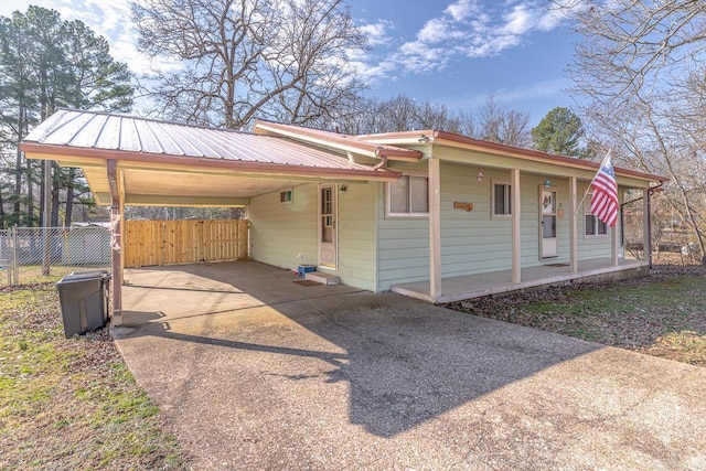 view of front of home with a carport, concrete driveway, fence, and metal roof