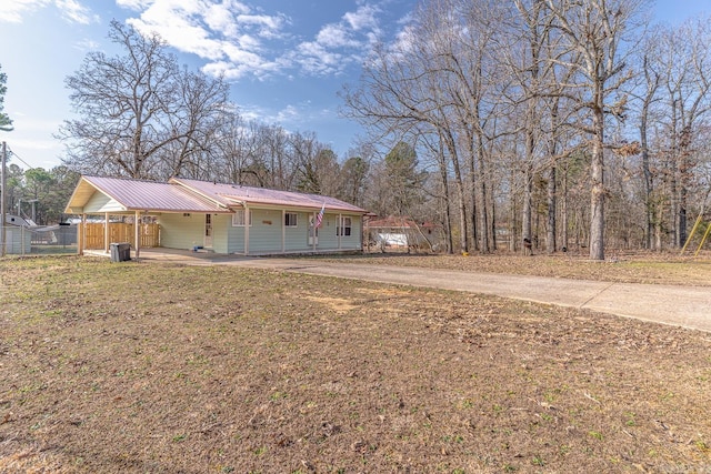 ranch-style home featuring a front lawn, metal roof, fence, and dirt driveway