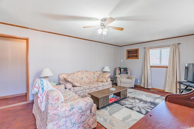 living area featuring baseboards, a ceiling fan, crown molding, and wood finished floors