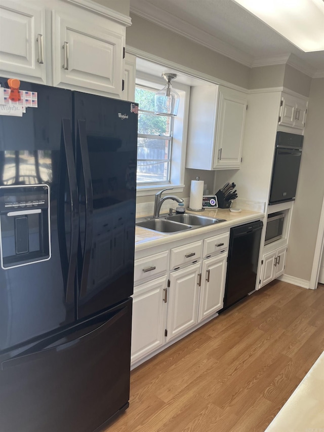 kitchen featuring crown molding, light wood-style floors, a sink, and black appliances