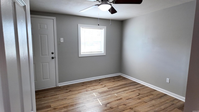 empty room featuring ceiling fan, baseboards, and wood finished floors