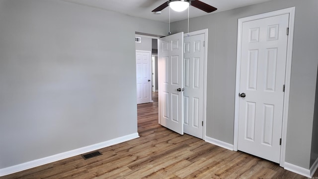 unfurnished bedroom featuring visible vents, a closet, baseboards, and wood finished floors