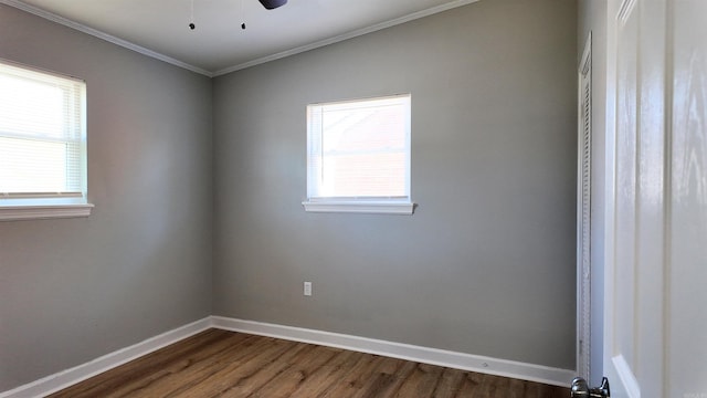 spare room with dark wood-style floors, plenty of natural light, baseboards, and crown molding