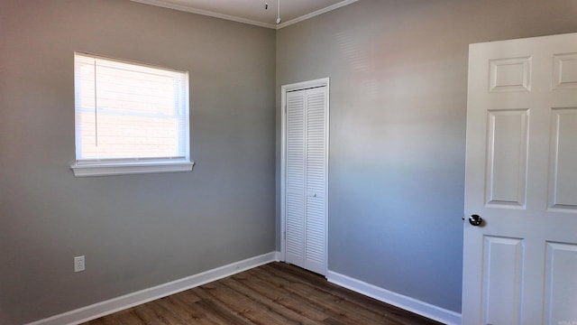 unfurnished bedroom featuring dark wood-style floors, a closet, ornamental molding, and baseboards