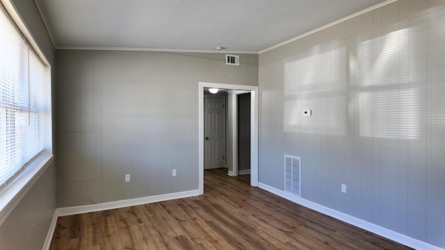 unfurnished room with visible vents, crown molding, baseboards, and wood finished floors