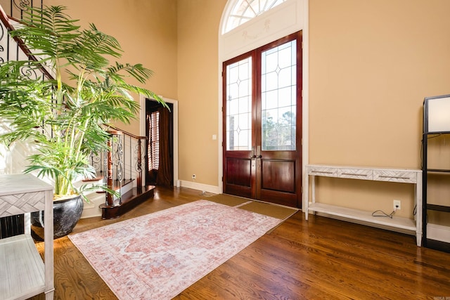 entryway featuring a towering ceiling, baseboards, wood finished floors, and french doors