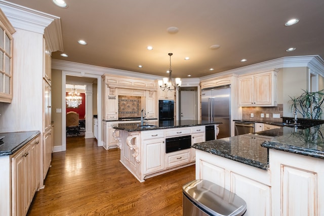 kitchen featuring stainless steel appliances, a notable chandelier, an island with sink, and dark wood-style floors