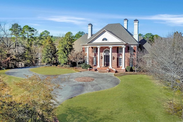 view of front facade featuring a front yard, brick siding, and driveway