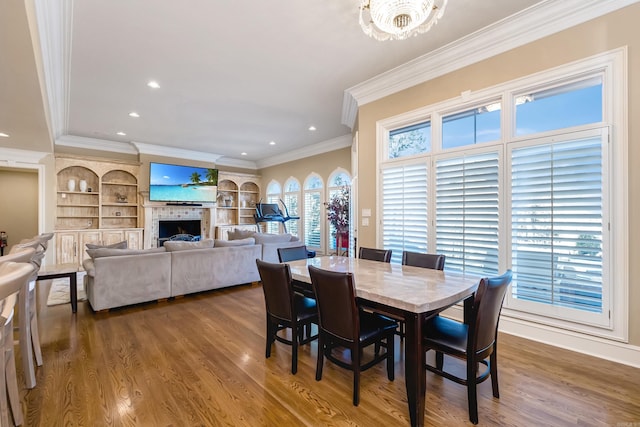 dining area with dark wood-style floors, crown molding, a fireplace, and built in features