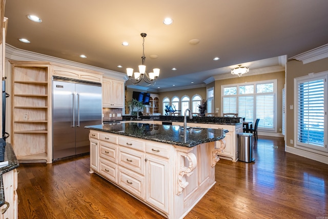 kitchen featuring a notable chandelier, stainless steel built in fridge, dark wood-style floors, open shelves, and a center island with sink