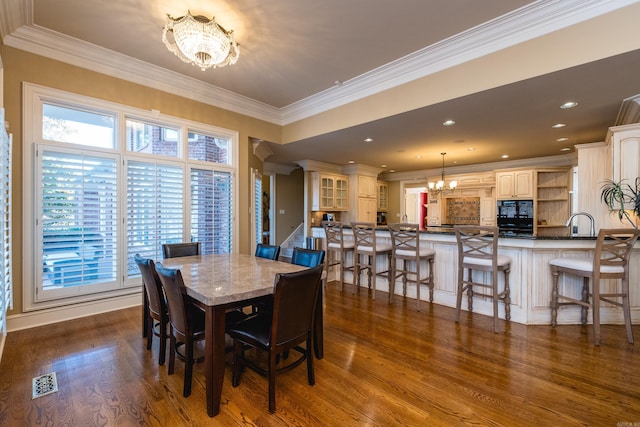 dining room featuring crown molding, dark wood-style flooring, visible vents, and a notable chandelier