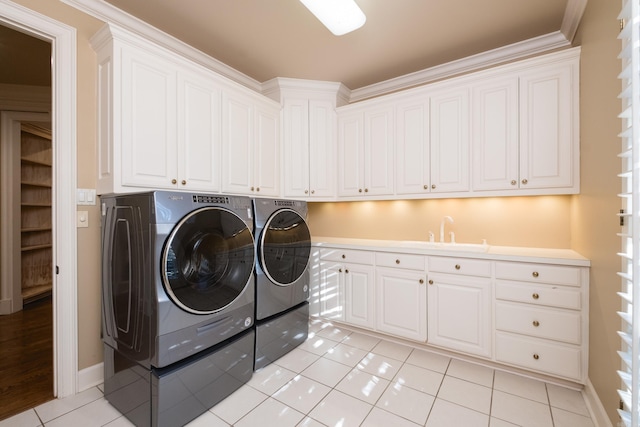 washroom with cabinet space, light tile patterned floors, baseboards, washing machine and clothes dryer, and a sink