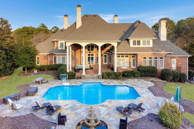 rear view of house with an outdoor fire pit, roof with shingles, a patio area, and brick siding