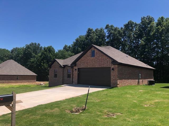 single story home with an attached garage, central air condition unit, brick siding, driveway, and a front lawn