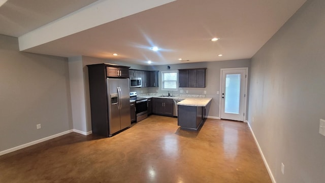 kitchen featuring baseboards, appliances with stainless steel finishes, finished concrete floors, light countertops, and a sink