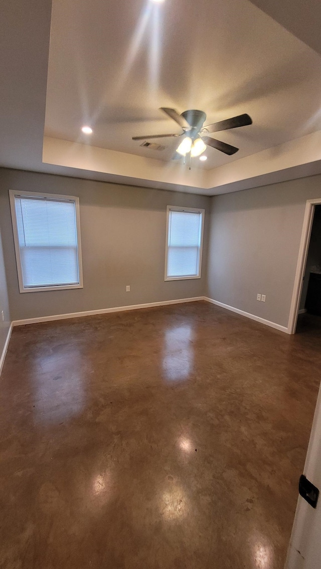 1108 Ava Ln, Paragould, AR 72450 - empty room featuring ceiling fan, visible vents, baseboards, a tray ceiling, and finished concrete floors