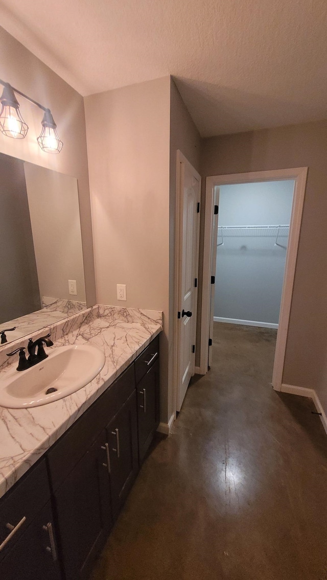 1108 Ava Ln, Paragould, AR 72450 - bathroom featuring a spacious closet, vanity, baseboards, and a textured ceiling