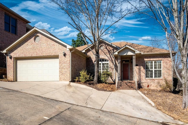 single story home featuring a garage, concrete driveway, and brick siding