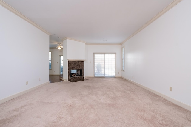 unfurnished living room featuring ornamental molding, light carpet, plenty of natural light, and a premium fireplace