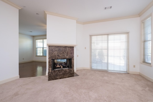 unfurnished living room featuring baseboards, visible vents, ornamental molding, carpet flooring, and a high end fireplace