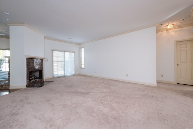 unfurnished living room featuring carpet, a fireplace, baseboards, and crown molding