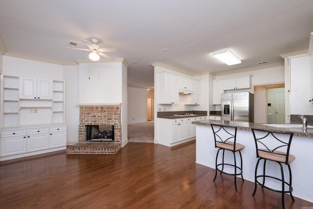 kitchen with crown molding, dark wood finished floors, white cooktop, stainless steel fridge, and a peninsula