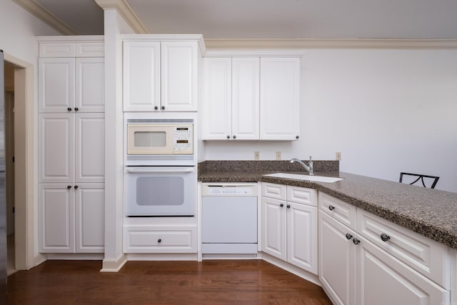 kitchen with white appliances, a sink, white cabinetry, ornamental molding, and dark wood finished floors