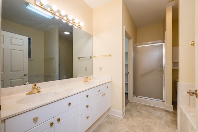 bathroom with double vanity, a stall shower, a sink, and baseboards