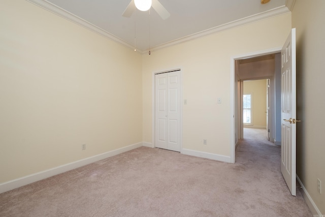 unfurnished bedroom featuring a closet, light colored carpet, crown molding, and baseboards